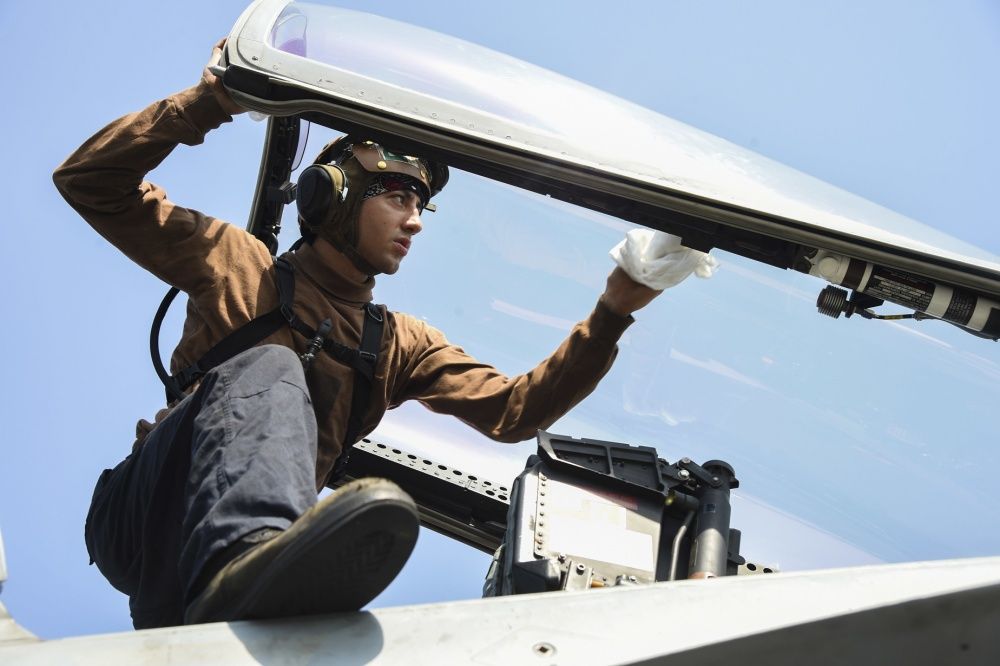 Airman Jonathan Stabilito, from Brentwood, N.Y., cleans the canopy of an F/A-18E Super Hornet assigned to the Sidewinders of Strike Fighter Squadron (VFA) 86 on the flight deck of the aircraft carrier USS Dwight D. Eisenhower (US Navy)