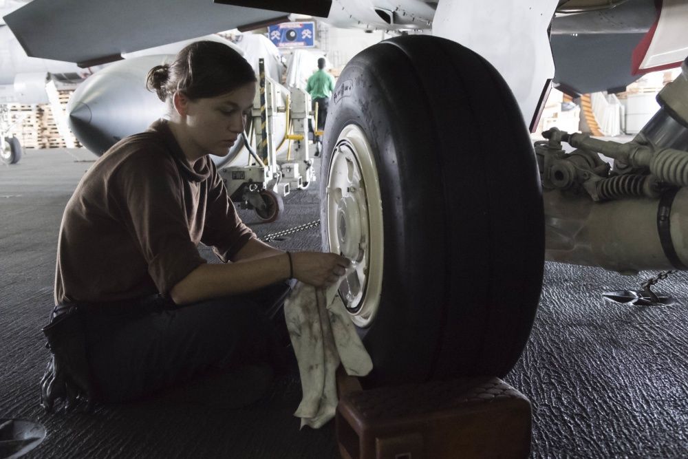 An Aviation Structural Mechanic assigned to the Fighting Swordsmen of Strike Fighter Squadron (VFA) 32 cleans the landing gear of a F/A-18E Super Hornet in the hangar bay of the aircraft carrier USS Dwight D. Eisenhower (US Navy)
