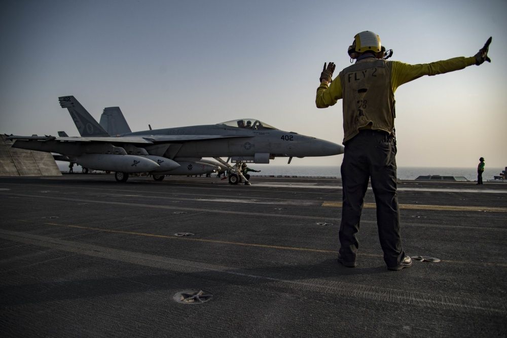 Aviation Boatswain's Mate 1st Class Jeremy Parrish, a native of Apopka, Fla., directs an F/A-18E Super Hornet assigned to the Gunslingers of Strike Fighter Squadron (VFA) 105 on the flight deck of the aircraft carrier USS Dwight D. Eisenhower (CVN 69) (Ike) (via US Navy)