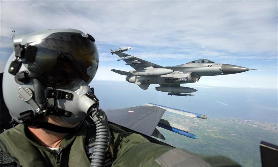 A pilot sits in the cockpit of a Dutch F16 with a second F-16 in the sky in the background (Dutch MoD)