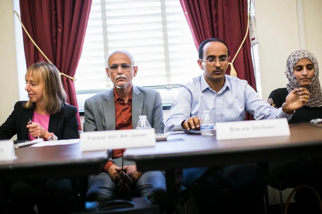Faisal bin Ali Jaber, center, with Medea Benjamin of Code Pink, left, and Baraa Shiban, who investigates drone strikes.Credit...T.J. Kirkpatrick for The New York Times