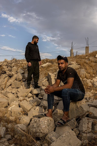Abdul Aziz Ahmed Araj, right, and his brother Saddam amid the ruins of the warehouse where their brother and other family members were killed. (Image by Ivor Prickett for The New York Times)