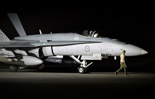 A RAAF Aircraft Technician assists with start-up checks as a pilot sits insided an F/A-18A Hornet fighter aircraft in preparation for a night time sortie. (Aus MoD)