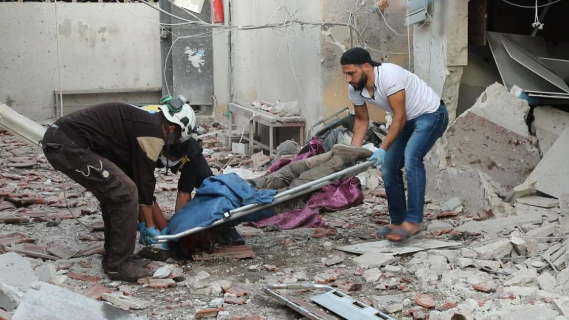Image of a White Helmet and a civilian carrying the body of one of the victims of the bombing on Afrin on June 12, 2021. (Image posted by Al Araby)