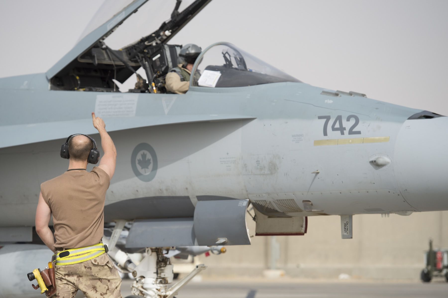 Camp Patrice Vincent, Kuwait. 11 June 2015 – A Royal Canadian Air Force technician gives a thumbs up to a CF-188 Hornet pilot during pre-flight checks at the flight line at Camp Patrice Vincent, Kuwait during Operation IMPACT (OP Impact, DND)