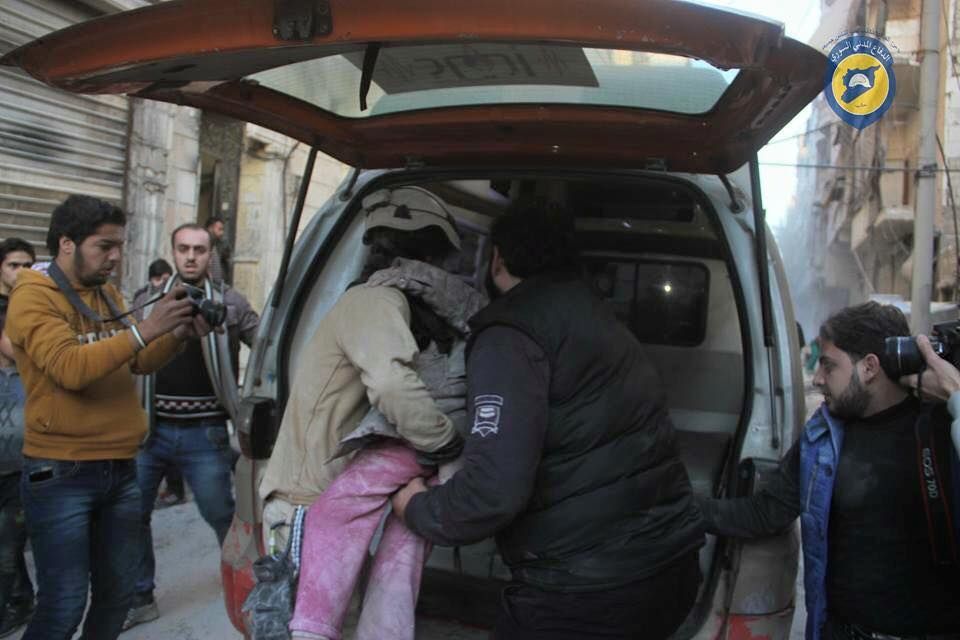 The White Helmets place the body of a wounded person in an ambulance following airstrike on the Al Ferdos neighbourhood, Dec 15th (via White Helmets)